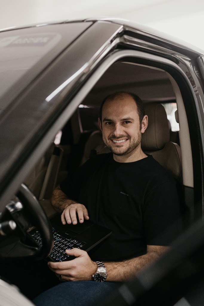 Thiago Dotta no carro, com o notebook no colo